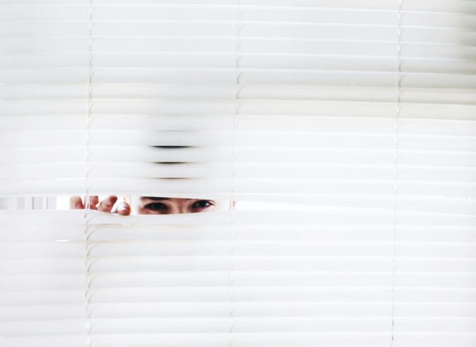 A man lurking behind closed blinds.